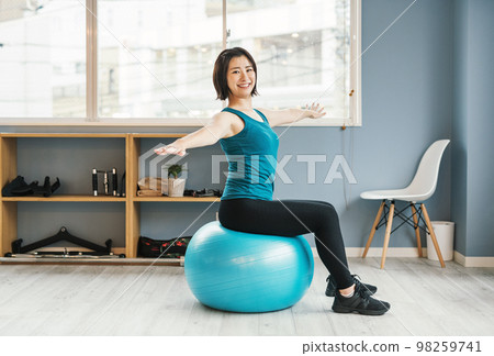 Woman riding a balance ball at the gym Woman riding a balance ball at the gym 98259741