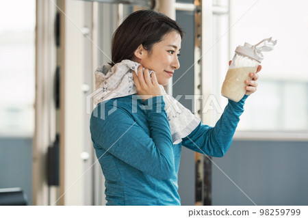 A woman who drinks protein after muscle training at the gym A woman who drinks protein after muscle training at the gym 98259799