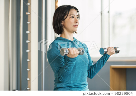 做肌肉訓練的婦女使用鐵列陣在健身房 98259804