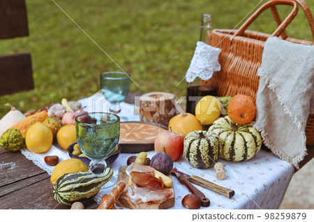 picnic in autumn park. Food, drinks, picnic basket on a wooden table in the garden. Cozy lunch picnic in autumn park. Food, drinks, picnic basket on a wooden table in the garden. Cozy lunch 98259879