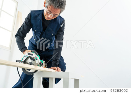 Male carpenter DIY cutting wood with a circular saw 98263002