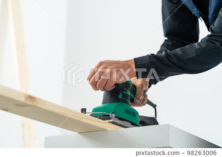 Man sanding wood with an electric file carpenter DIY 98263006