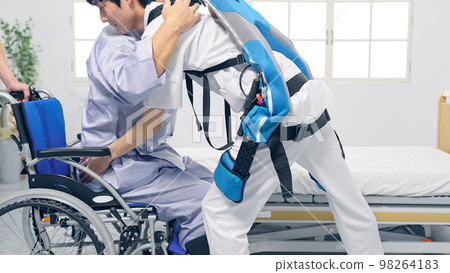 一位穿著動力輔助服的護士抱著病人轉移輔助設備 一位穿著動力輔助服的護士抱著病人轉移輔助設備 98264183