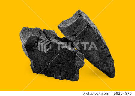 Black charcoal isolated on yellow background 98264876