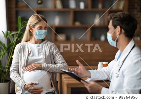 Young Pregnant Female Wearing Face Mask Having Check Up With Therapist Doctor 98264956