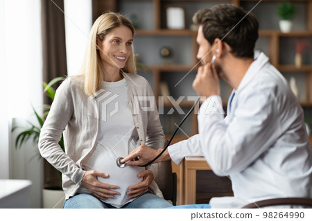 Male Gynecologist With Stethoscope Examining Belly Of Pregnant Female Patient Male Gynecologist With Stethoscope Examining Belly Of Pregnant Female Patient 98264990