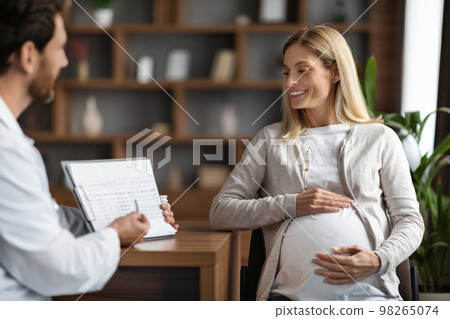 Male Doctor Showing Clipboard With Medical Test Results To Pregnant Female Patient Male Doctor Showing Clipboard With Medical Test Results To Pregnant Female Patient 98265074