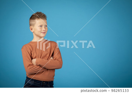 Portrait Of Handsome Preteen Boy With Folded Arms Standing Over Blue Background 98265133
