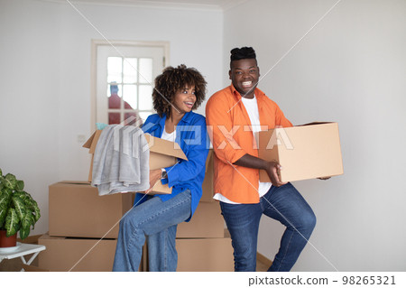 Moving Concept. Portrait Of Cheerful Black Couple With Cardboard Boxes In Hands Moving Concept. Portrait Of Cheerful Black Couple With Cardboard Boxes In Hands 98265321