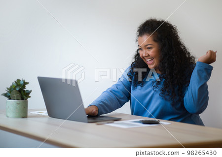 Emotional happy plus size young woman working from home Emotional happy plus size young woman working from home 98265430