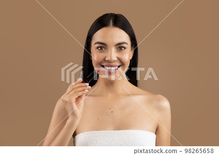 Beautiful half-naked woman showing her lipstick, beige background 98265658