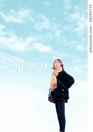 A young woman with a blue sky and a beige muffler A young woman with a blue sky and a beige muffler 98265715