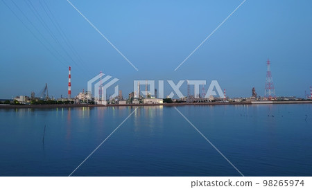 A night view of a faintly lit factory reflected in the water A night view of a faintly lit factory reflected in the water 98265974