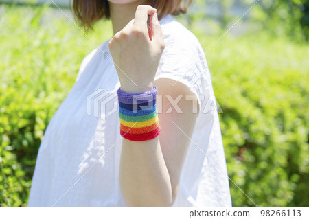 A woman wearing a rainbow-colored wristband outdoors faceless 98266113