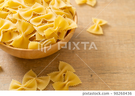 Dry uncooked farfalle pasta in bowl 98268436