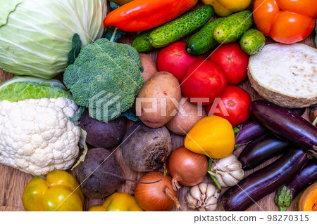 Various vegetables are laid out on a wooden table. Large assortment of vegetables food. pumpkin cabbage broccoli pepper tomatoes carrots and others 98270315