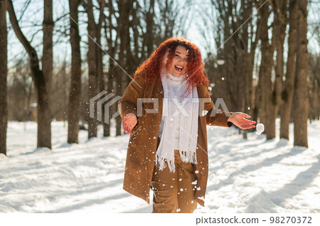 Fat caucasian woman playing snowballs in the park.  98270372