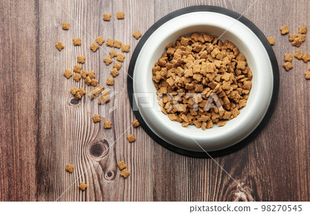 A bowl of dog food on a wooden floor. A bowl of dog food on a wooden floor. 98270545