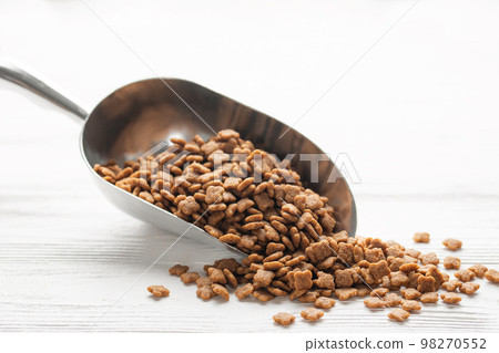 Dry pet food in scoop on white wooden background. Dry pet food in scoop on white wooden background. 98270552