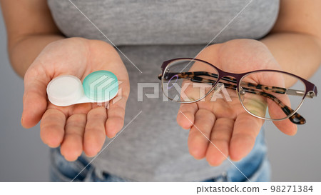 A woman makes a choice between lenses and glasses. A woman makes a choice between lenses and glasses. 98271384