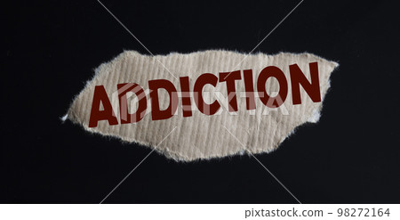 The word addiction is written on brown cardboard and black background. 98272164