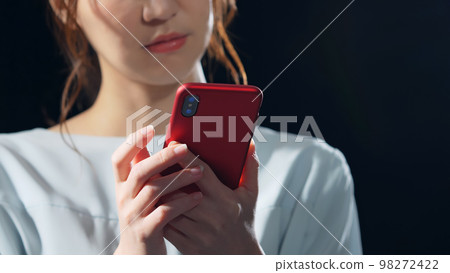A woman using a smartphone in a dark room 98272422
