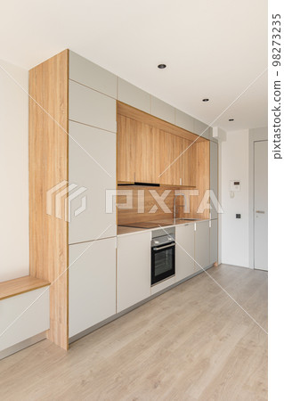Contemporary minimal kitchen at empty refurbished apartment. Wooden furniture and modern appliances Contemporary minimal kitchen at empty refurbished apartment. Wooden furniture and modern appliances 98273235