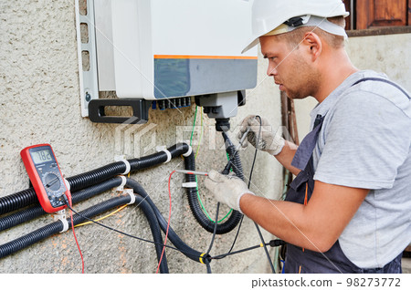 Man electrician installing solar panel system. Inspector in helmet and gloves making electrical wiring inverter and electric box. Concept of alternative and renewable energy. Man electrician installing solar panel system. Inspector in helmet and gloves making electrical wiring inverter and electric box. Concept of alternative and renewable energy. 98273772