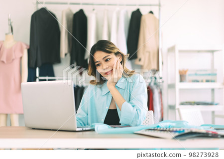 Young adult asian woman tailor designer using laptop computer for internet online marketing 98273928