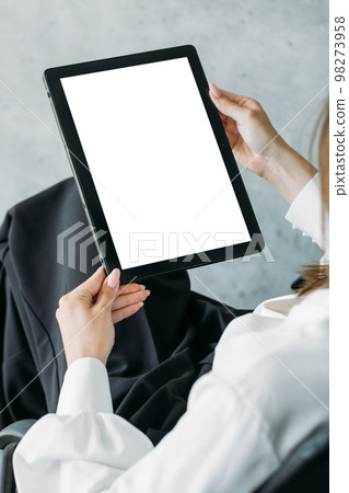 Virtual connection. Digital mockup. Online meeting. Unrecognizable woman holding tablet computer with blank screen in light room interior. 98273958