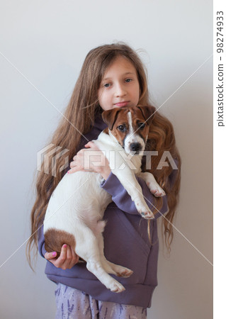 A ten-year-old girl is playing with a puppy. 98274933