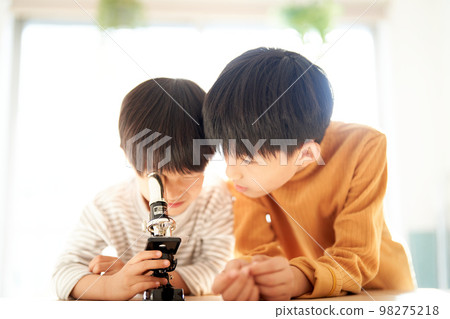 Two boys looking into a microscope with great interest Lifestyle image Two boys looking into a microscope with great interest Lifestyle image 98275218