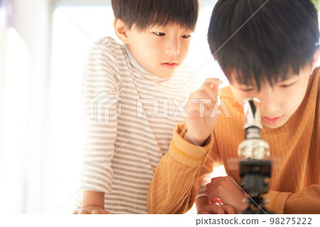 Two boys looking into a microscope with great interest Lifestyle image 98275222