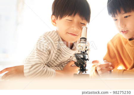 Two boys looking into a microscope with great interest Lifestyle image 98275230