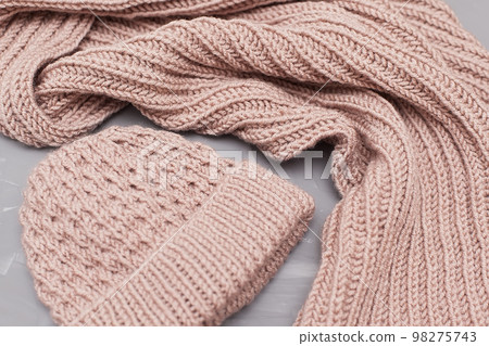 Knitted winter clothes, neatly stacked on a white background. The surface of women's woolen things, textiles. Close-up knitted texture. The background is gray. Casual clothes. 98275743