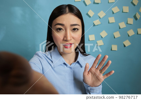 Entrepreneur holding mobile phone having a video call with colleague gesturing with her hand while explaining her point of view. Asian woman brainstorming remotely with coworker. 98276717