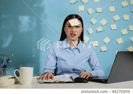 Female startup worker with a confused expression trying to understand the financial reports generated on software of laptop computer. Office employee working late to meet deadline. 98276809