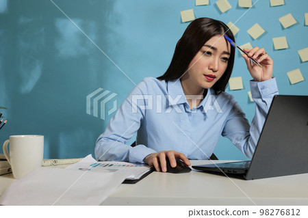 Asian business woman thinking about work strategy and about business focus plan. Pensive entrepreneur with ideas to develop a new marketing project, looking for solutions. 98276812