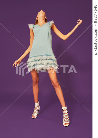 Image of pretty young blonde girl in blue cocktail dress dancing on purple background in studio Image of pretty young blonde girl in blue cocktail dress dancing on purple background in studio 98277640