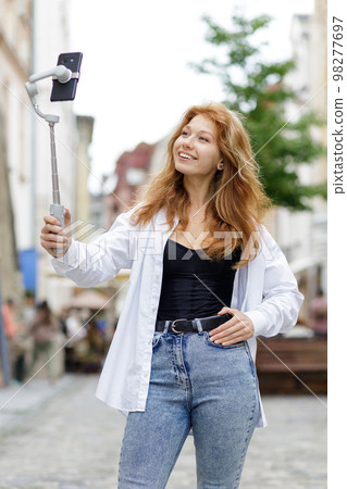 Young redheaded beautiful woman walking and using her mobile phone 98277697