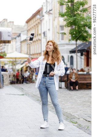 Young redheaded beautiful woman walking and using her mobile phone 98277718