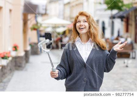 Young red-hair beautiful woman walking and using her mobile phone 98277754
