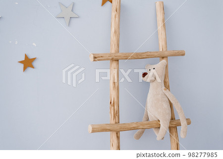 Soft toy bear sits on a wooden staircase in the decor of the children's room Soft toy bear sits on a wooden staircase in the decor of the children's room 98277985