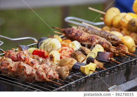 Assorted grilled meat with vegetables over the coals on a barbecue Assorted grilled meat with vegetables over the coals on a barbecue 98278035