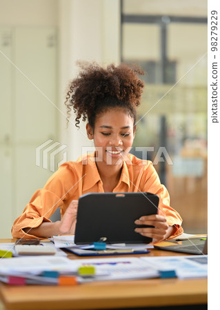 Portrait of smiling African American investor checking financial data on digital tablet Portrait of smiling African American investor checking financial data on digital tablet 98279229