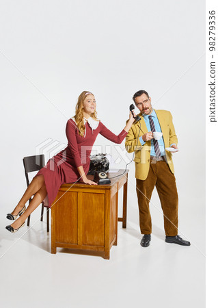 Cheerful woman, personal assistant holding phone handset for businessman drinking coffee. Secretary help. Working routine 98279336