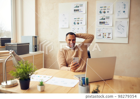 Smiling Businessman Relaxing Office. Positive Guy Holding Smartphone At Table Smiling Businessman Relaxing Office. Positive Guy Holding Smartphone At Table 98279354