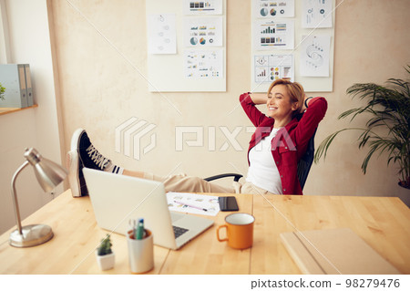Woman Relaxing At Office. Cheerful Woman Keeping Hands Behind Head Woman Relaxing At Office. Cheerful Woman Keeping Hands Behind Head 98279476