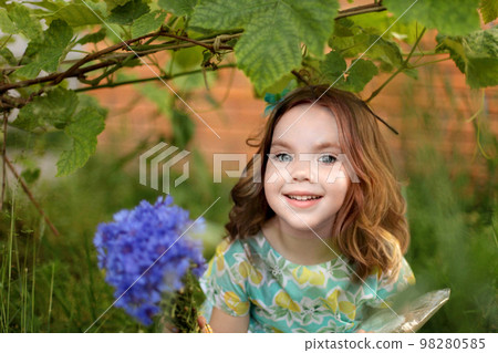 Cute little girl in autumn park holding bunch of yellow leaves. High quality photo 98280585