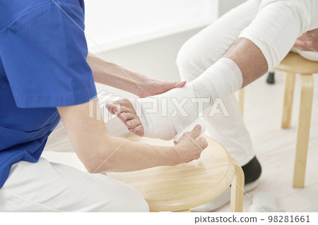 一名醫生包紮他的腿無面 98281661